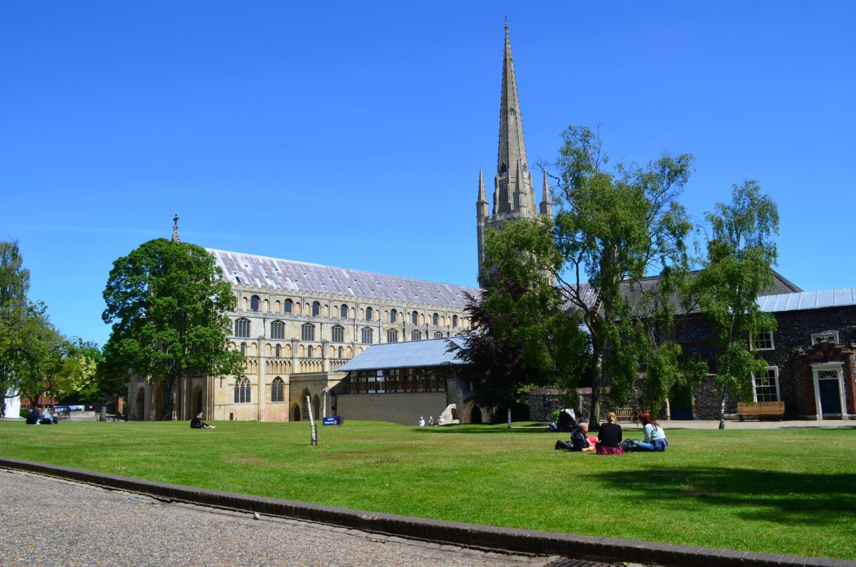 Photo of Norwich cathedral and surrounding gardens on a sunny day. 