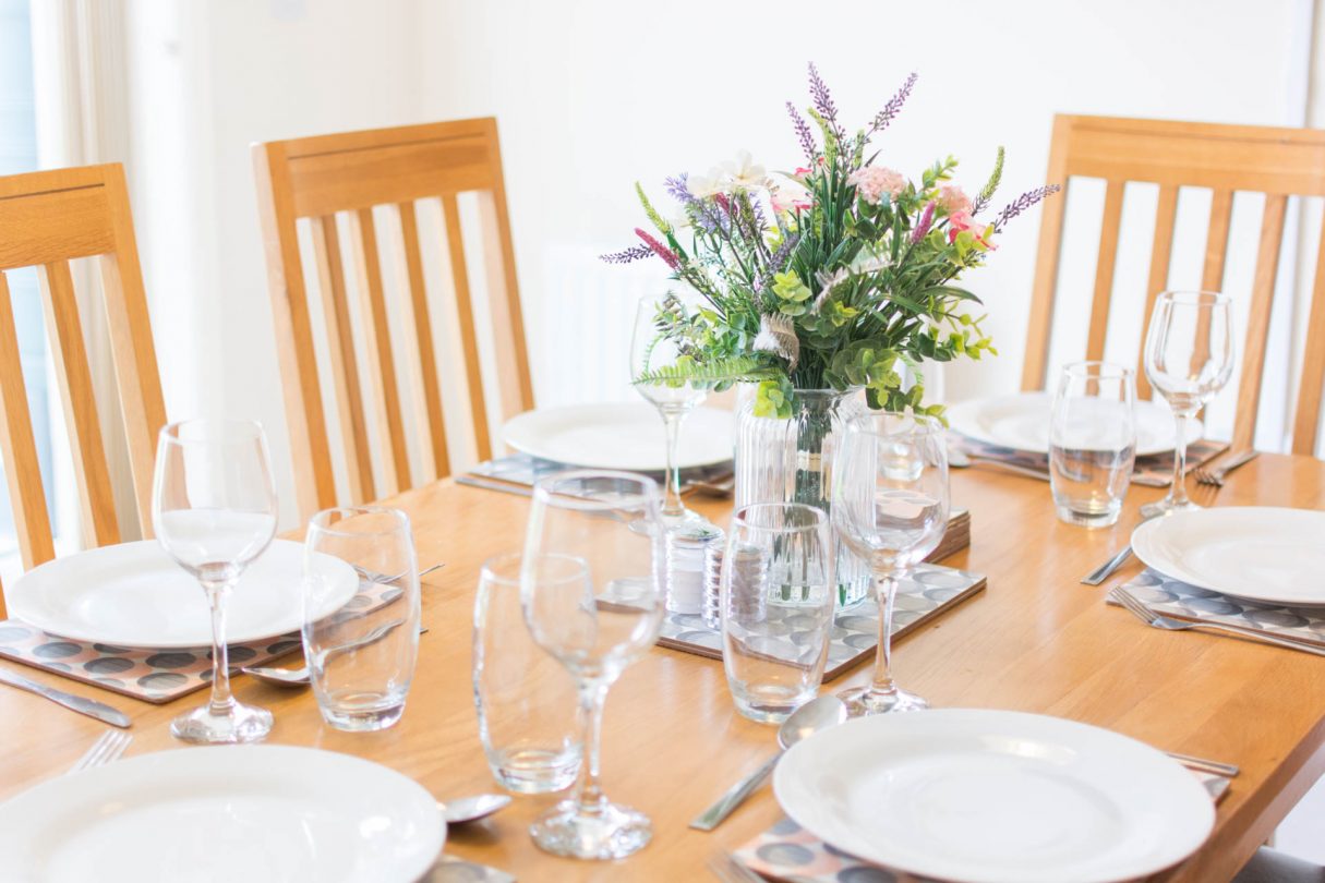 Close up shot of glassware and crockery on family dining table.