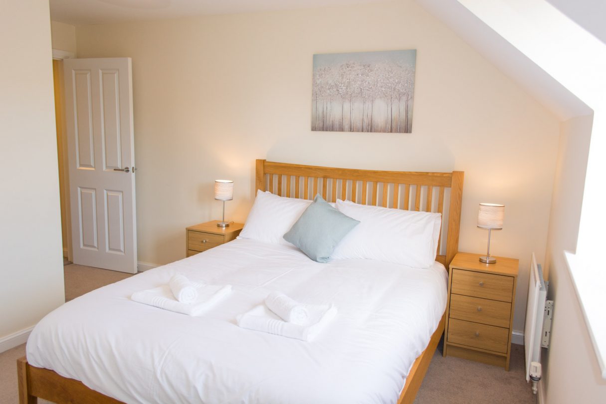 King-sized bedroom with bedside tables either side of the wooden framed bed.