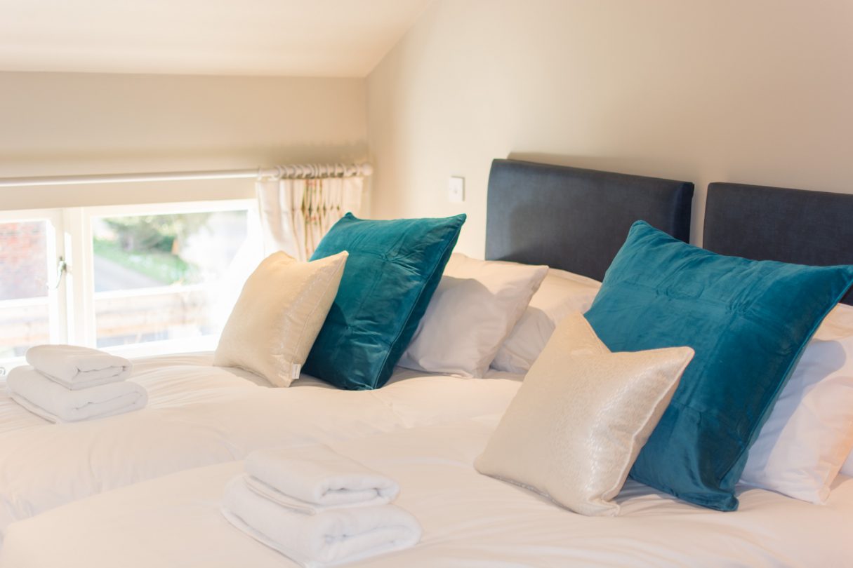 Upstairs twin room with white linen and large blue pillows.