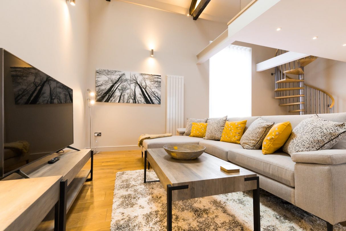 Sofa and television with winding staircase in the background.