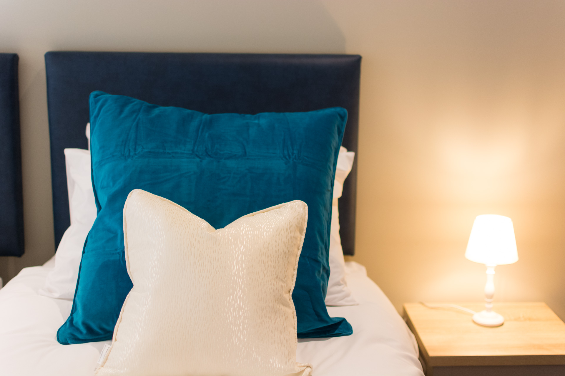 Close up photo of large blue and small white pillows in a twin bedroom.