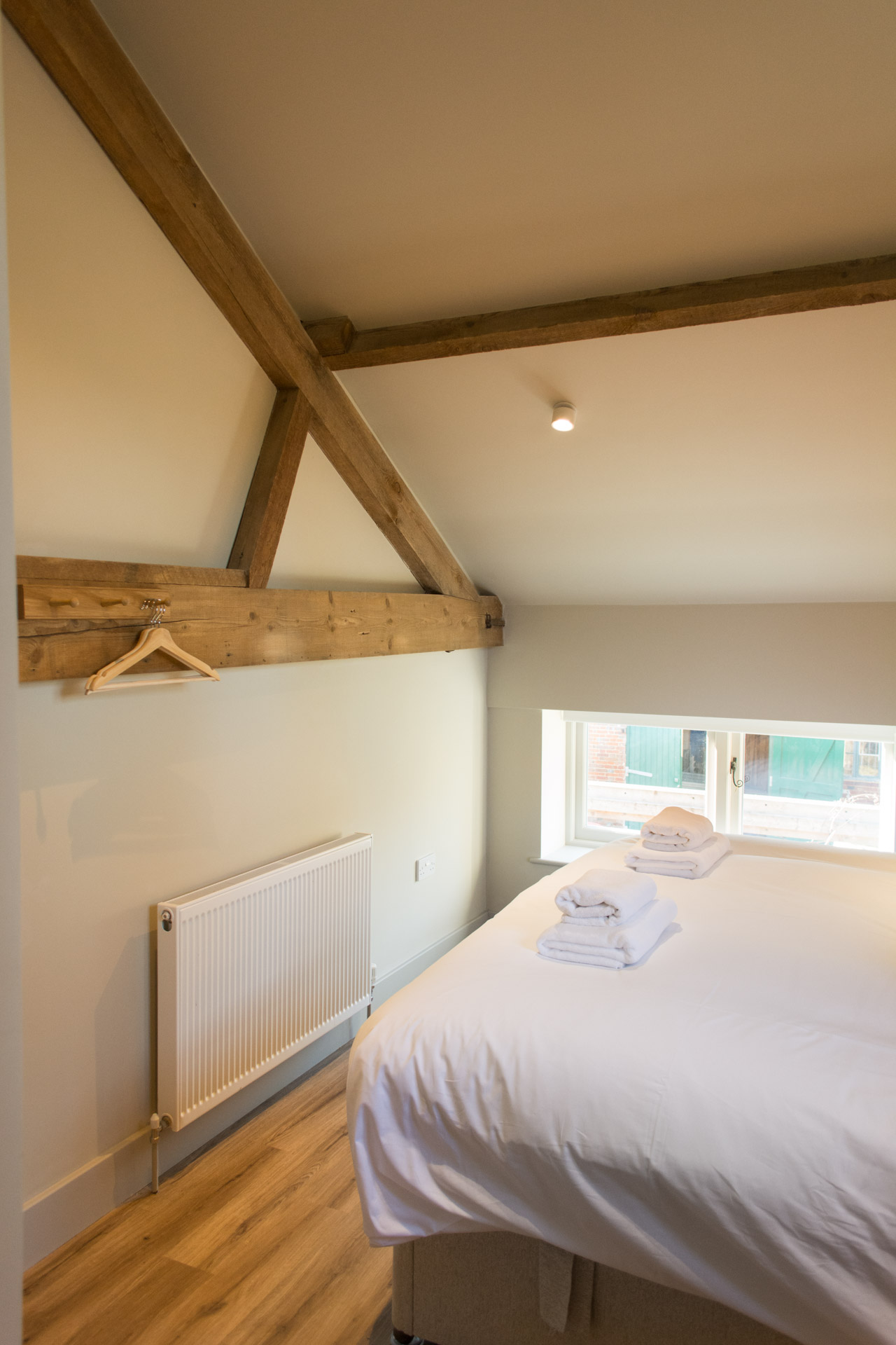 Super-king bedroom showing wooden beams on the walls and ceiling.