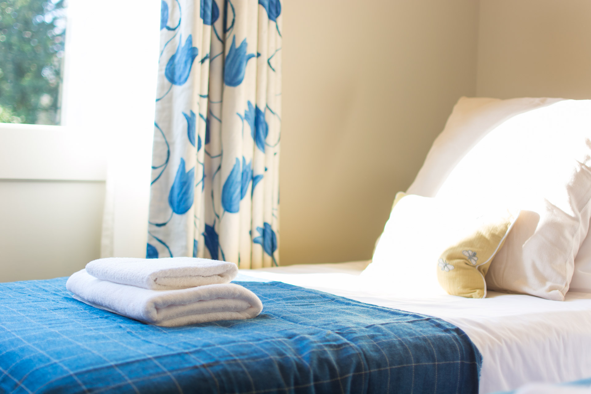 Close up photo of white towel on twin room bed.