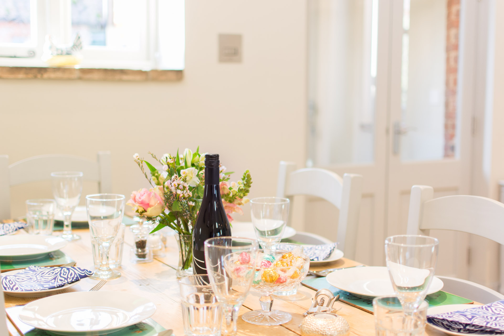 Close up of crockery and glasses with a flower in the middle of the dining table.