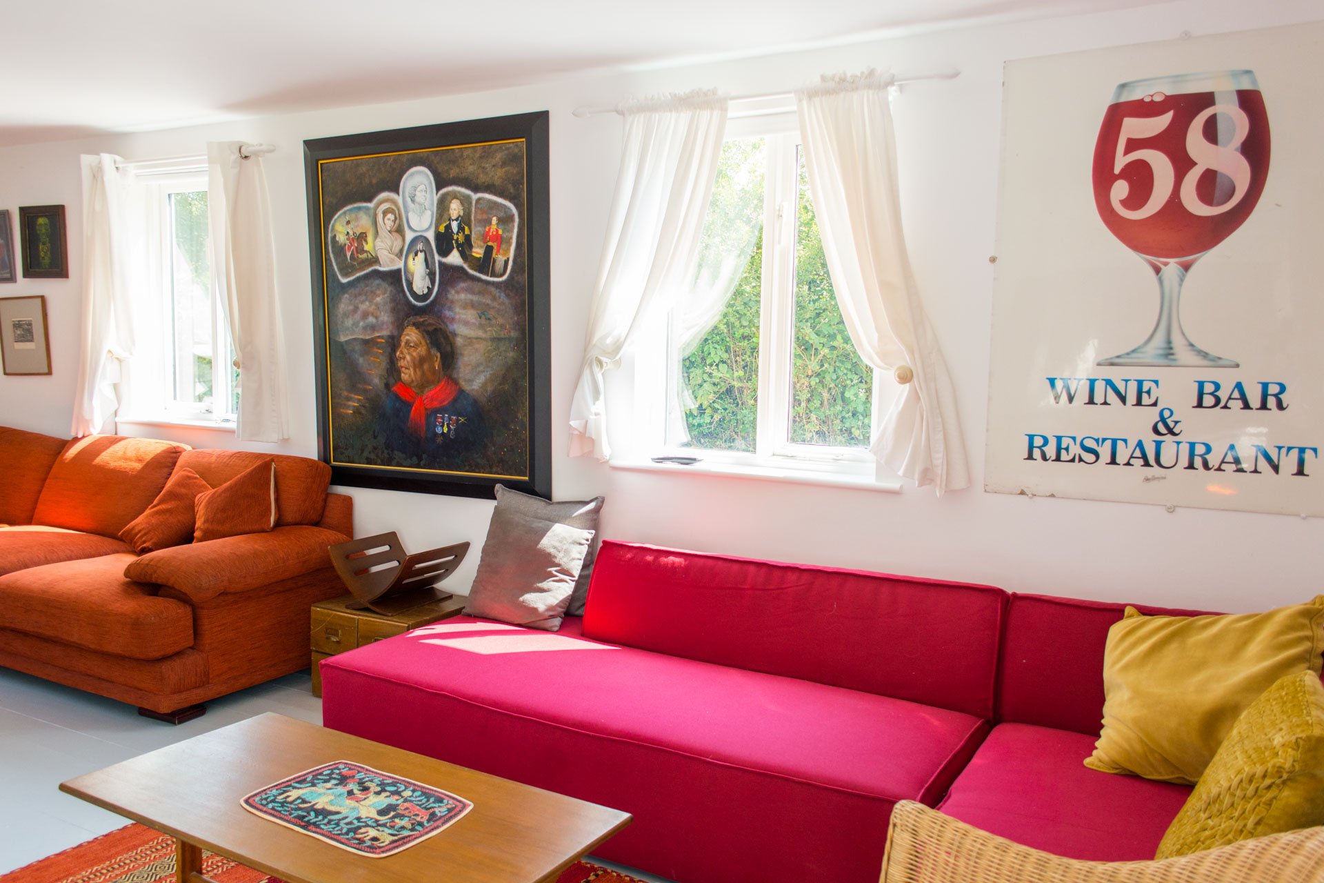 red sofa under a window, next to local artwork.