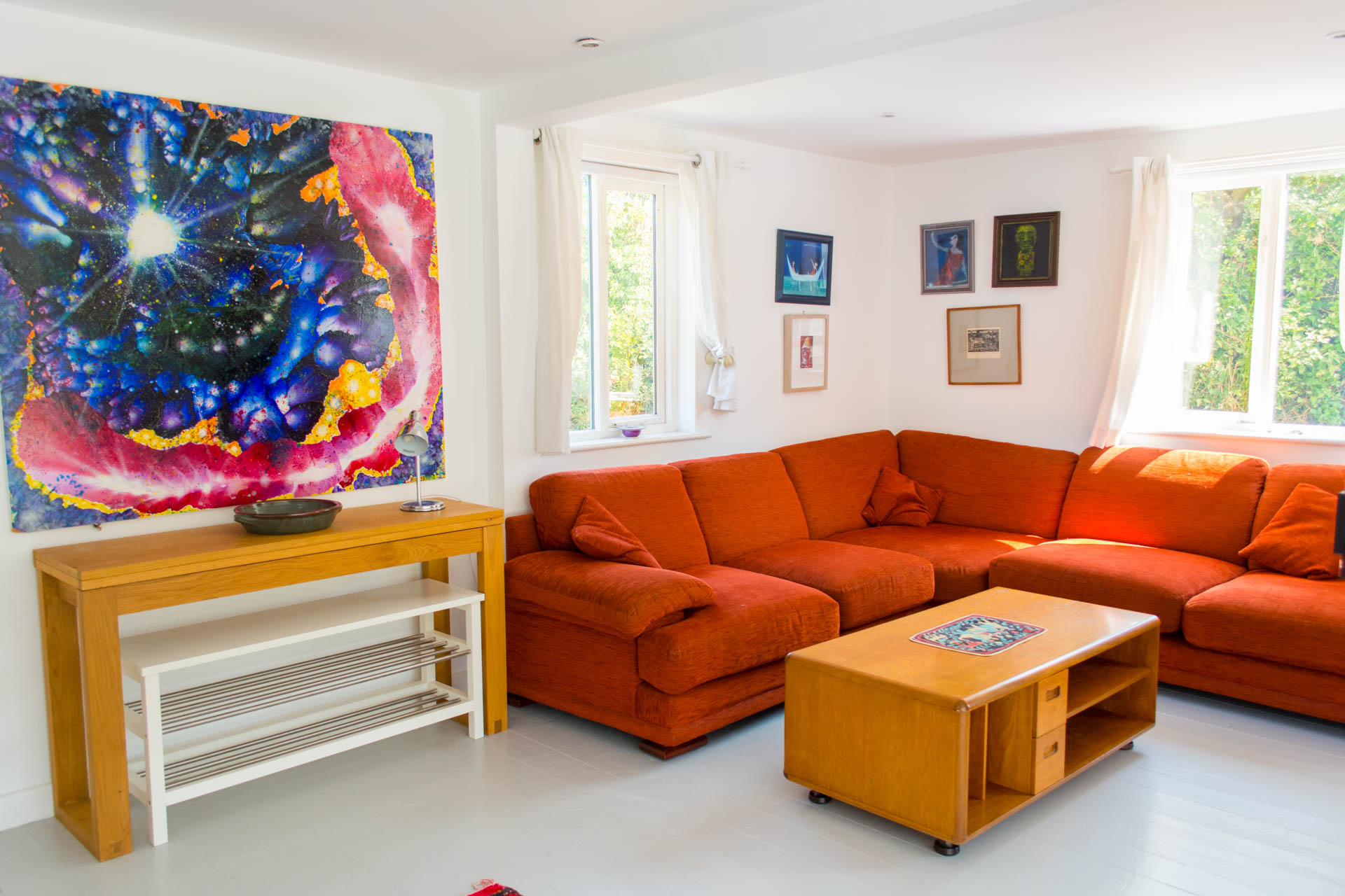 Photo of spacious living area and coffee table with colourful art work on the walls.