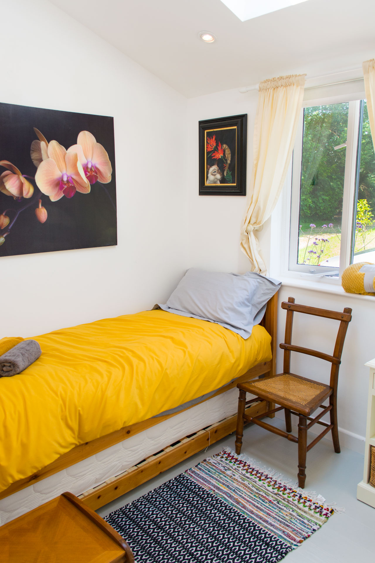 Single bedroom showing a bed with a yellow duvet and grey pillow.