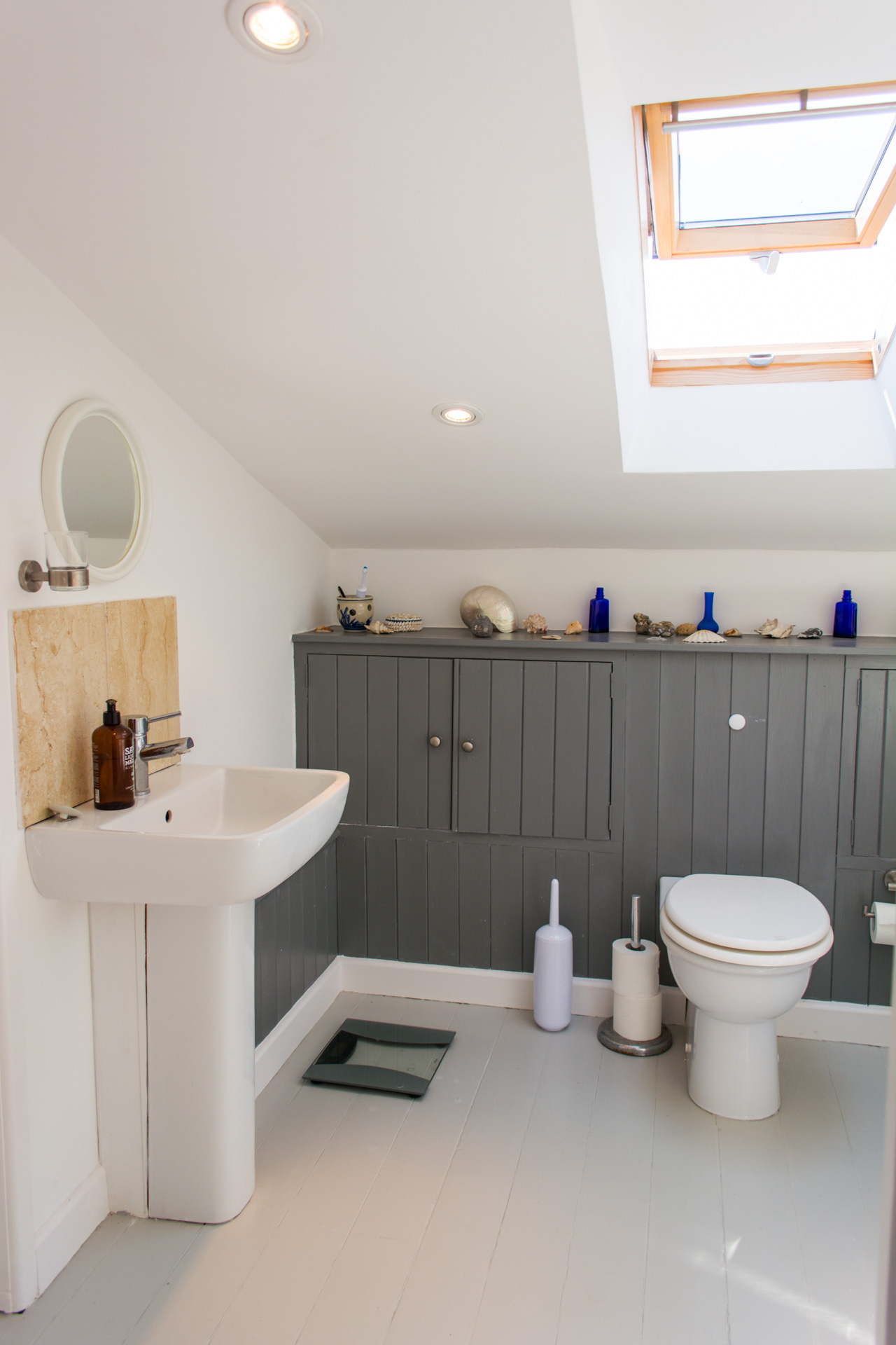 Second bathroom photo showing the toilet and sink, with a ceiling window letting in natural light.