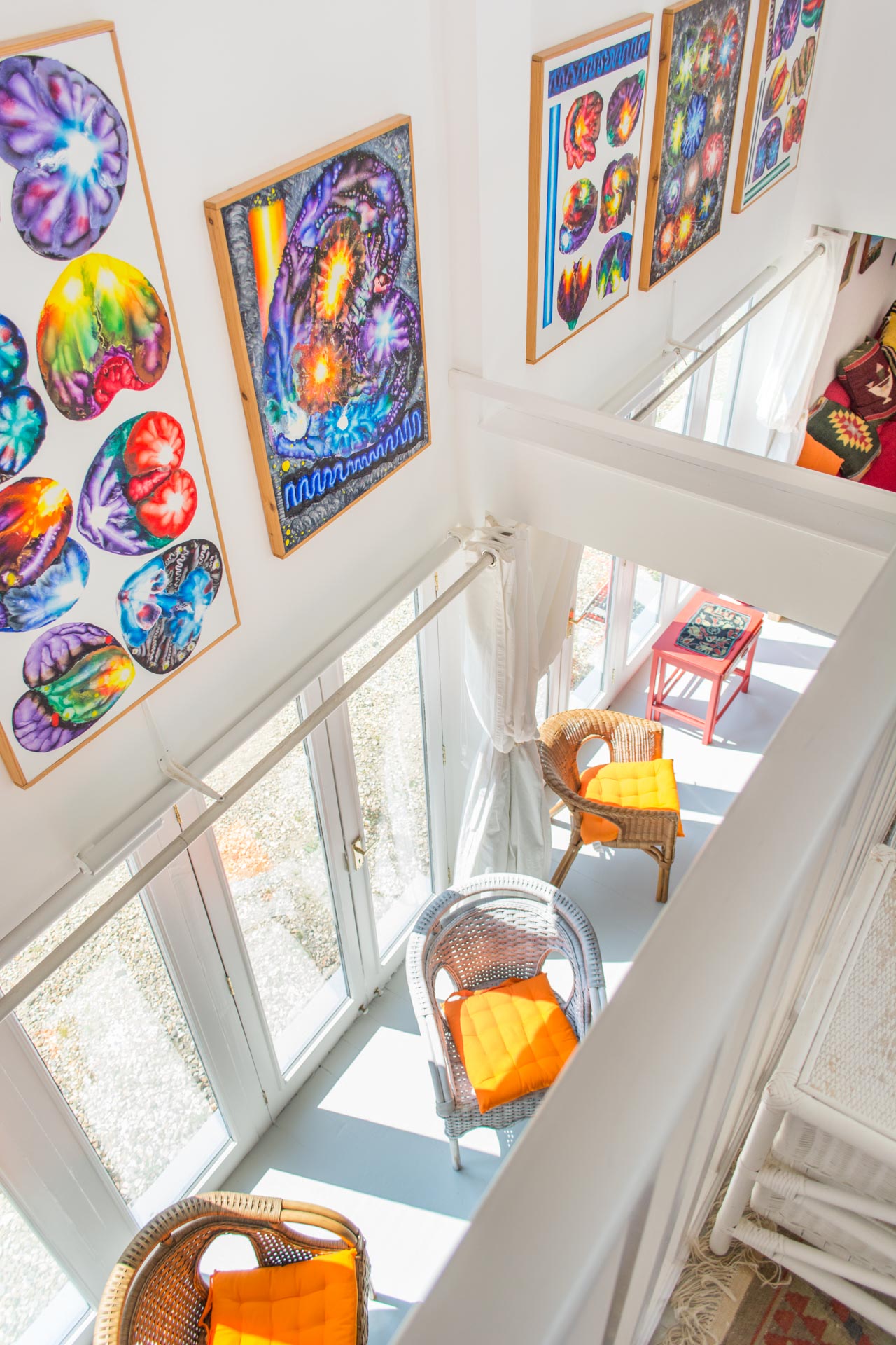 Photo taken from the mezzanine level showing colourful artwork on the walls and chairs on the ground floor.