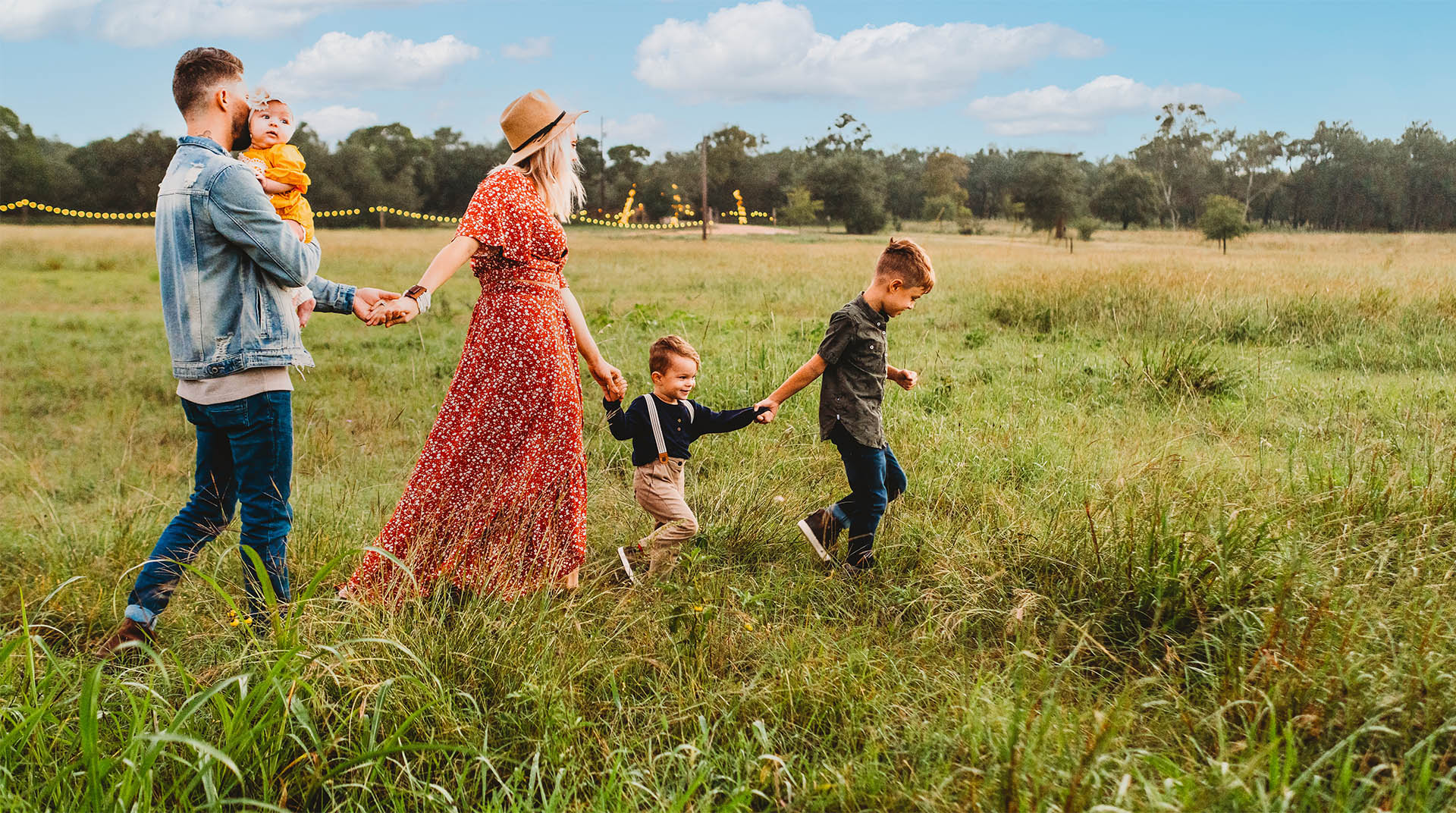 Family exploring a rural setting across fields on a sunny day.